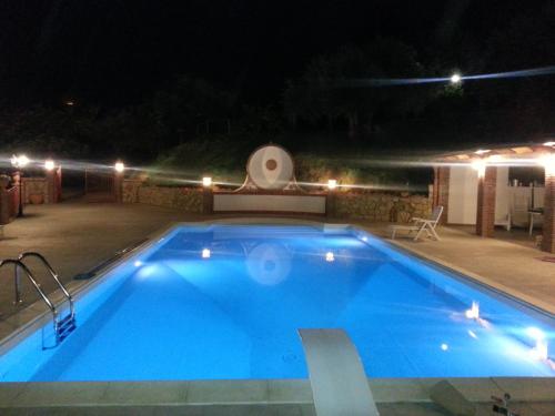 a large blue swimming pool at night with lights at L'Uliveto in Reitano