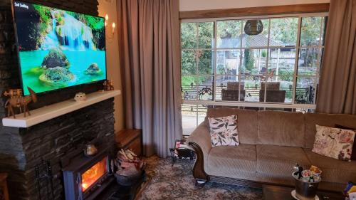 a living room with a couch and a flat screen tv at Hahndorf House B&B in Hahndorf