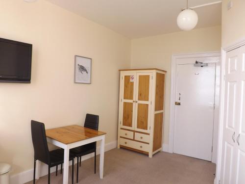 a dining room with a table and a cabinet at The Edenhurst Guesthouse in Weymouth