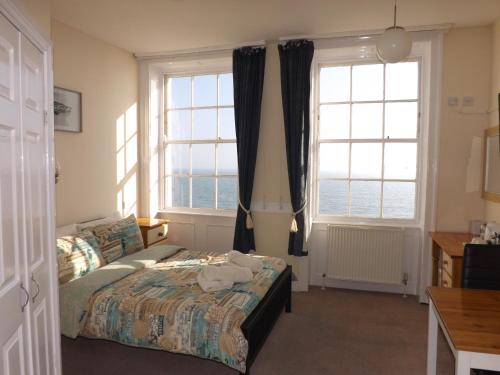 a bedroom with a bed and two large windows at The Edenhurst Guesthouse in Weymouth
