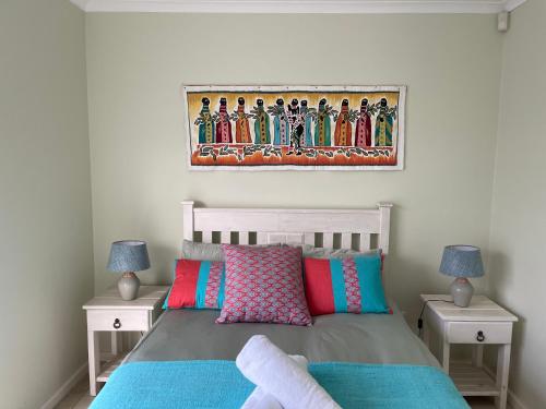 a bedroom with a bed with a painting on the wall at Sea Breeze in Stilbaai