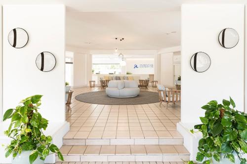 a living room with white walls and potted plants at The Signature Level at Grand Palladium Sicilia Resort & Spa in Campofelice di Roccella