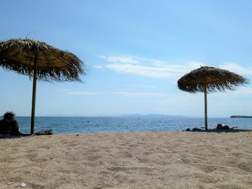 two straw umbrellas on a beach with the ocean at Galini Palace in Athens