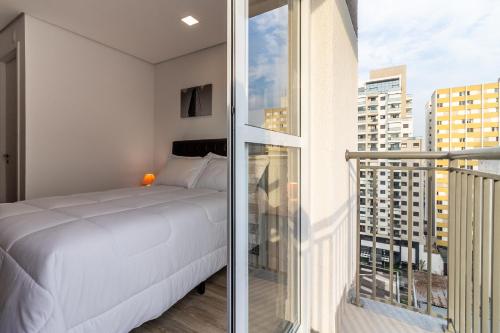 a bedroom with a white bed and a balcony at Studio Bela Vista Teatro Renault in Sao Paulo