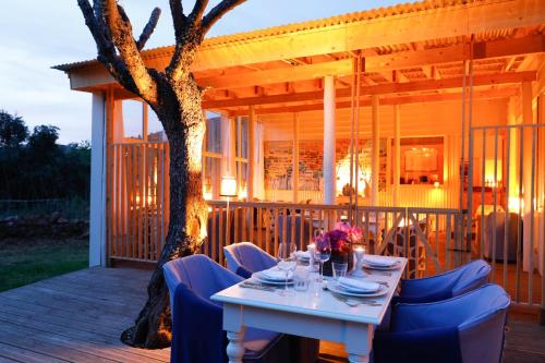 a white table and chairs on a deck with a tree at Herdade da Matinha Country House & Restaurant in Cercal