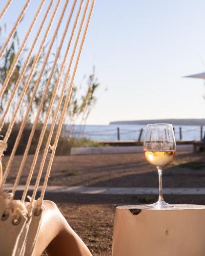 a woman sitting in a hammock with a glass of wine at Hostal Aigua Clara in Playa Migjorn