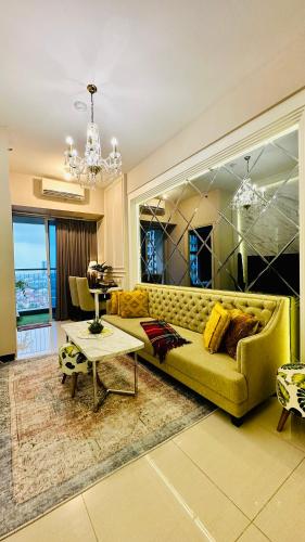 a living room with a yellow couch and a table at Luxury 2 Bed Room Anderson Apartment Pakuwon Mall in Surabaya