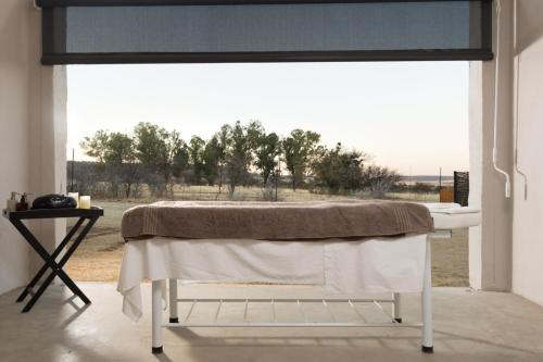 een kamer met een tafel en een groot raam bij Mont d'Or Monte Bello Estate in Bloemfontein