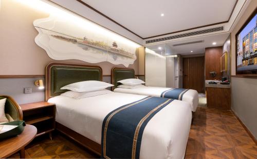 a bedroom with two beds and a desk and a tv at Nostalgia S Hotel Beijing CCTV in Beijing