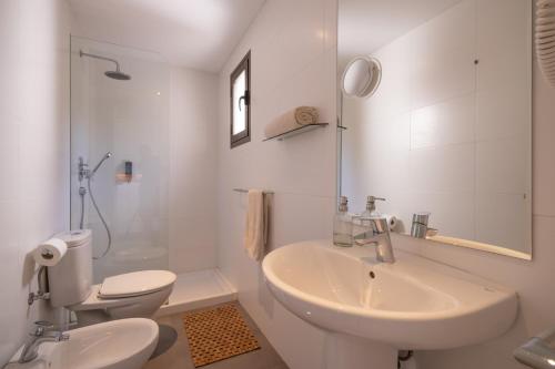 a white bathroom with a sink and a toilet at Hostal Aigua Clara in Playa Migjorn