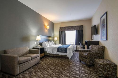 a hotel room with a bed and two chairs at Comfort Inn & Suites in Fort Saskatchewan