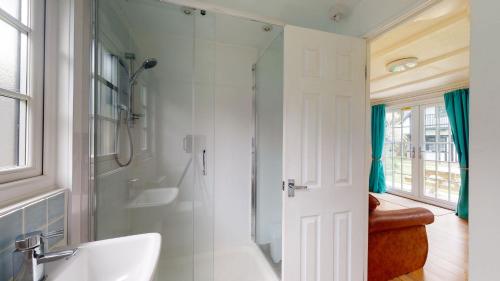 a white bathroom with a shower and a sink at 31 Tudor Court, Tolroy Manor in Hayle