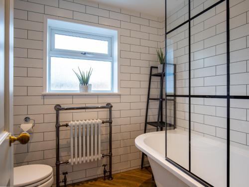 a bathroom with a tub and a toilet and a window at Trinity Cottage in Shottery