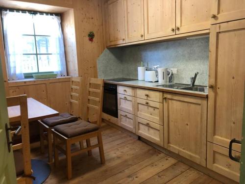 cocina con armarios de madera, fregadero y mesa en Villa Mathilde - Tirolese, en Prato allo Stelvio