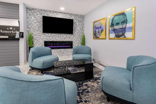 a waiting room with blue chairs and a fireplace at AmericInn by Wyndham Quincy in Quincy