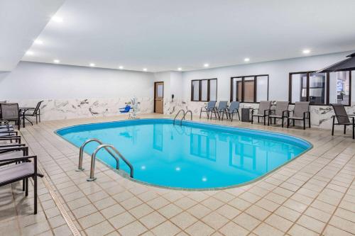 a pool in a hotel with chairs and tables at AmericInn by Wyndham Quincy in Quincy