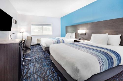 a hotel room with two beds and a flat screen tv at AmericInn by Wyndham Quincy in Quincy