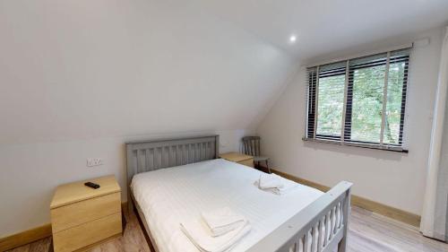 um quarto com uma cama branca e uma janela em 48 Trevithick Court, Tolroy Manor em Hayle