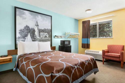 Pokój hotelowy z łóżkiem i krzesłem w obiekcie Super 8 by Wyndham Findlay w mieście Findlay