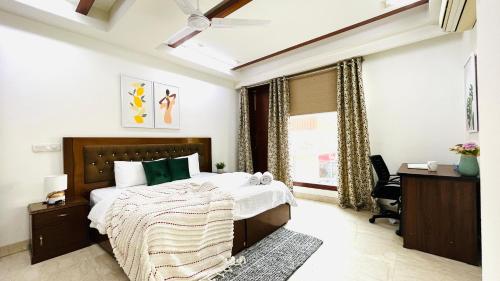 1 dormitorio con cama, escritorio y ventana en Olive Service Apartments - Green Park, en Nueva Delhi