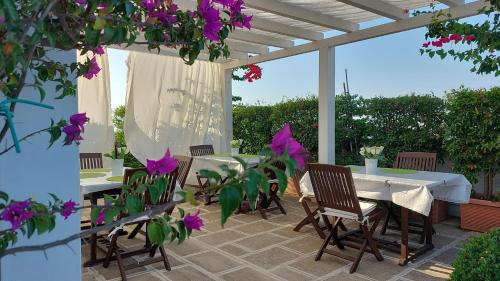 un patio con tavolo, sedie e fiori viola di B&B Corte Regina Esther a Veglie