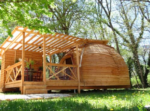 uma casa de hobbit de madeira com uma pérgola de madeira em Habitat Créateur - Hébergements insolites au camping municipal "Les Ecureuils" em Recoubeau