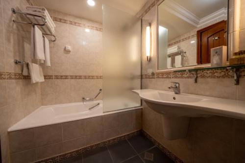 a bathroom with a tub and a sink and a mirror at Duja Chalet Ski Center in Sarıkamıs