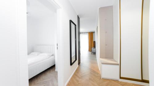a bedroom with a white bed and a mirror at Apartament Olivia - ACCO RENT in Gdańsk