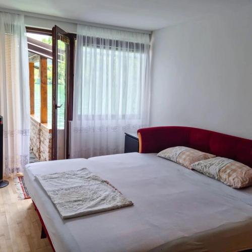 a bedroom with a bed with a red headboard and a window at Holiday Home Nur in Konjic