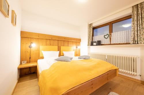 sypialnia z dużym łóżkiem i żółtym kocem w obiekcie Loewenzahn w mieście Grainau