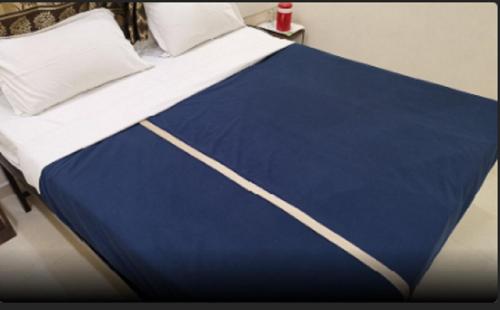 a bed with a blue and white sheet on it at Hotel Royal Treat in Kolhapur