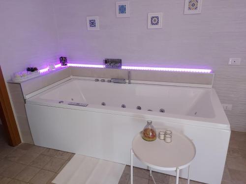 bañera blanca con mesa blanca y luces rosas en B&B Ferro di Cavallo, en Tívoli