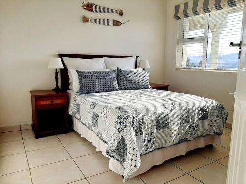 a bedroom with a bed with a black and white comforter at Umkhomo Place, Mangrove Beach Estate in Port Shepstone