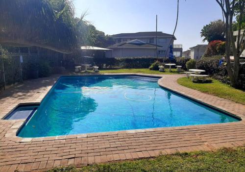 a swimming pool with blue water in a yard at Umkhomo Place, Mangrove Beach Estate in Port Shepstone