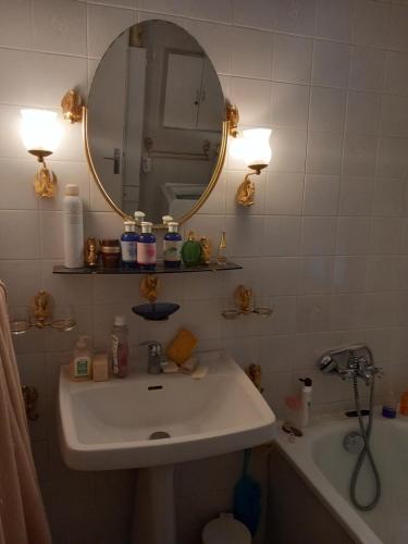 uma casa de banho com um lavatório, um espelho e uma banheira em La maison des amoureux de ballades dans le Jura 