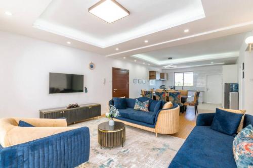 a living room with blue couches and a tv at Home Sweet Home in Nairobi