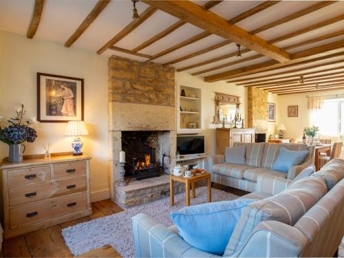 a living room with a couch and a fireplace at Swift Cottage in Blockley