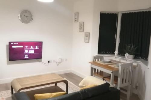 a living room with a couch and a tv on the wall at Lovely 1-Bedroom Flat in Hinckley, LE10 in Hinckley