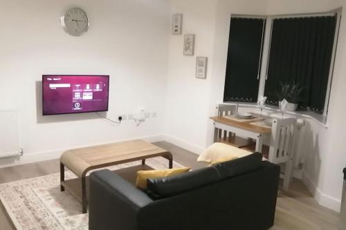 een woonkamer met een bank, een tafel en een tv bij Lovely 1-Bedroom Flat in Hinckley, LE10 in Hinckley