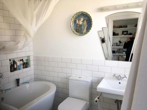 a bathroom with a tub and a toilet and a sink at Stunning Richmond Maisionette with rooftop patio in Richmond