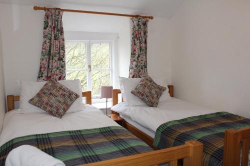 two beds in a room with a window at Avondale in Llangollen