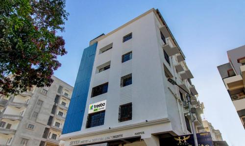 a tall white building with a blue at Treebo Trend Seven Suites in Nagpur