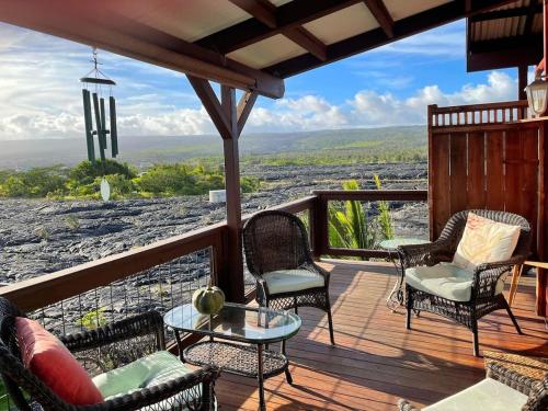 a porch with chairs and a table and a view at COZY OFF GRID LAVA HOME - 2 Stories, Ocean View in Pahoa