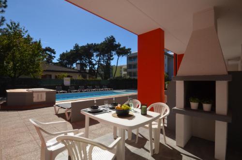 a patio with a table and chairs and a fireplace at Appartamenti Villa Simona in Bibione