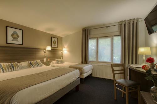 a hotel room with two beds and a desk at Aerotel Versailles Saint Cyr - L'étape du Silence in Saint-Cyr-lʼÉcole