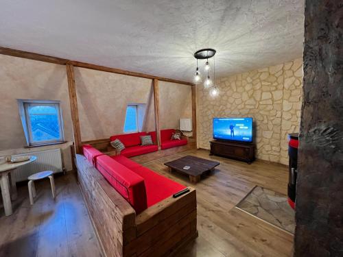 a living room with a red couch and a tv at Apartment Chalet mit Kamin in Plauen