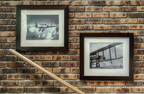 a brick wall with two framed pictures of an airplane at Aerotel Versailles Saint Cyr - L'étape du Silence in Saint-Cyr-lʼÉcole