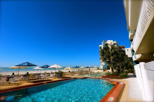 a swimming pool with chairs and umbrellas and the beach at Shoreline Island Resort - Exclusively Adult in St Pete Beach