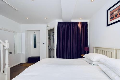 1 dormitorio con 2 camas blancas y cortina morada en Mews House, en Brighton & Hove