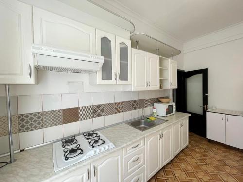 een keuken met witte kasten en een fornuis met oven bij DAY & NIGHT in Odessa